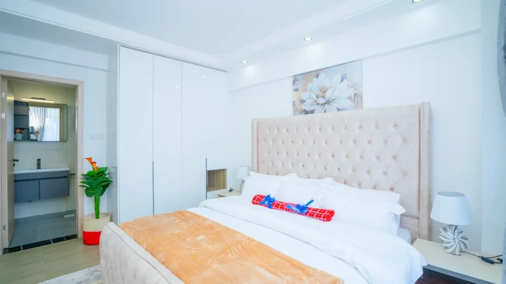 En-suite master bedroom with upholstered headboard, built-in wardrobes, and vanity bathroom at Orchid Residency