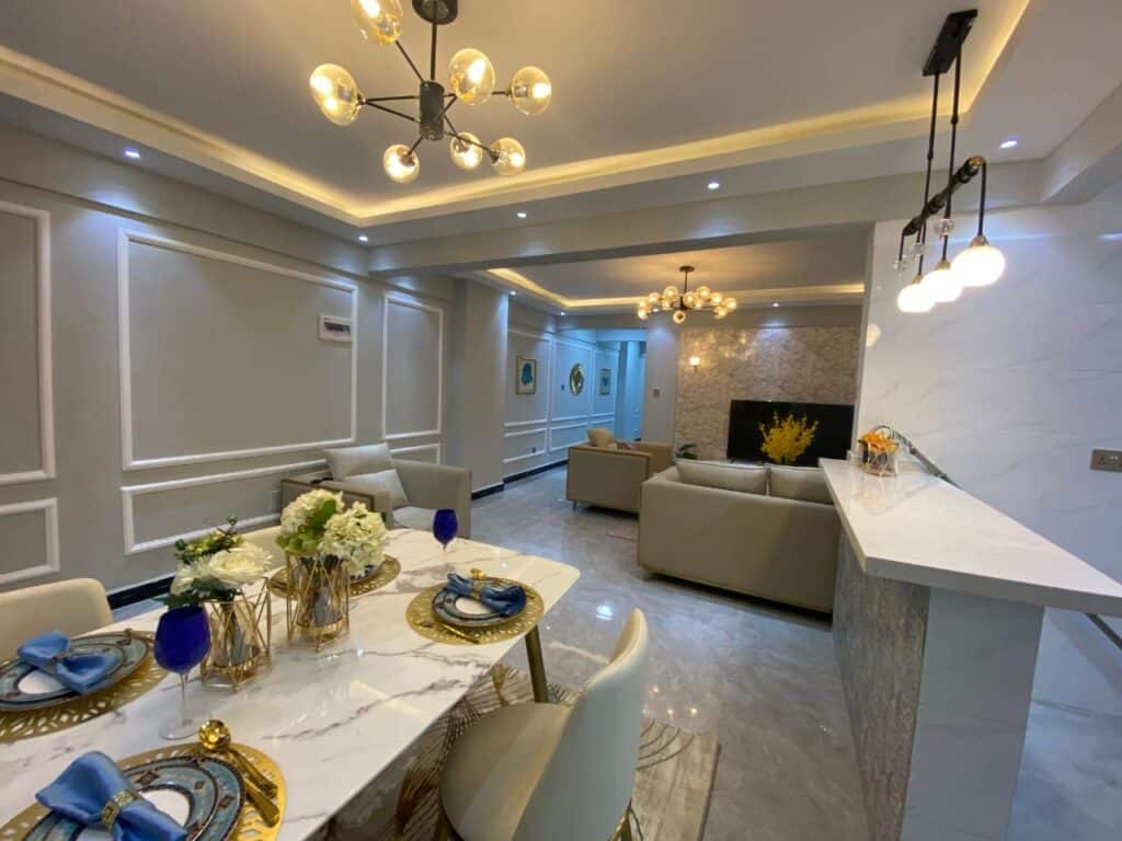 Elegant open-plan dining space with a marble-top dining table, designer pendant lighting, and breakfast bar at Diamond Homes in Kileleshwa, Nairobi.