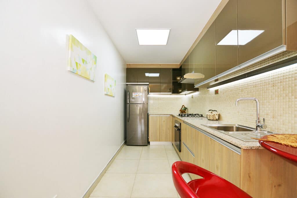 Modern fitted kitchen featuring wood-grain cabinetry, integrated gas stove, tile backsplash, and refrigerator space at Minah Heights Westlands in Westlands, Nairobi.
