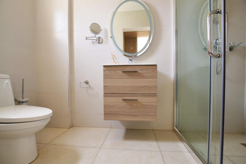 Contemporary en-suite bathroom with glass walk-in shower enclosure, floating sink vanity, and backlit mirror at Minah Heights Westlands in Westlands, Nairobi.