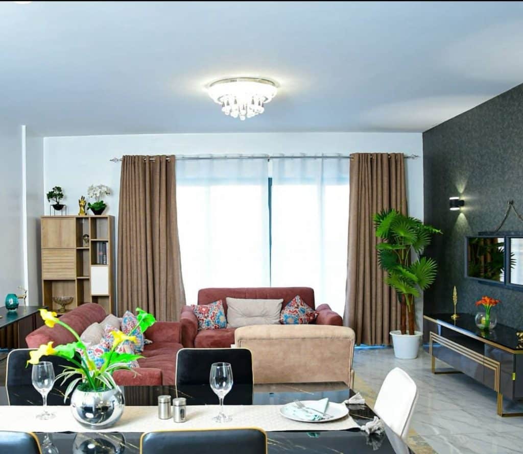 Furnished sitting lounge with wall-mounted TV panel and chandelier at Ambra Heights Kileleshwa