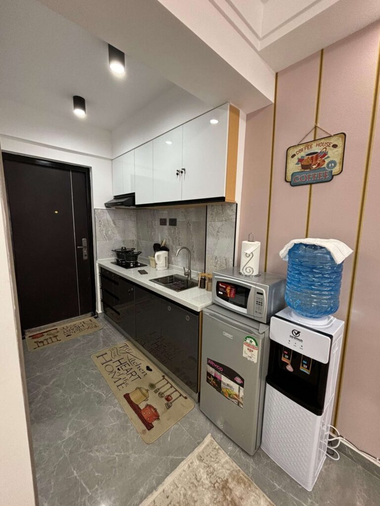 Fitted kitchenette with black lower cabinetry, white wall units, and microwave at Gatundu Heights Kileleshwa