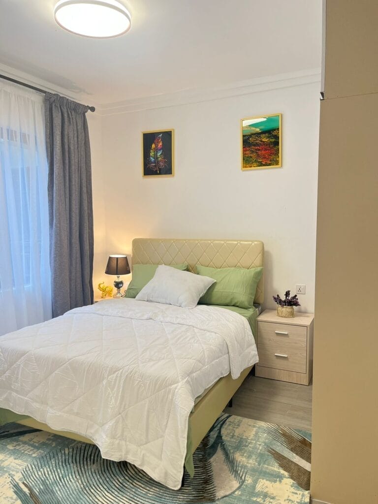 Elegantly furnished bedroom with quilted leather headboard, nightstand, and ambient lighting at New Rise Gardens in Syokimau, Nairobi.