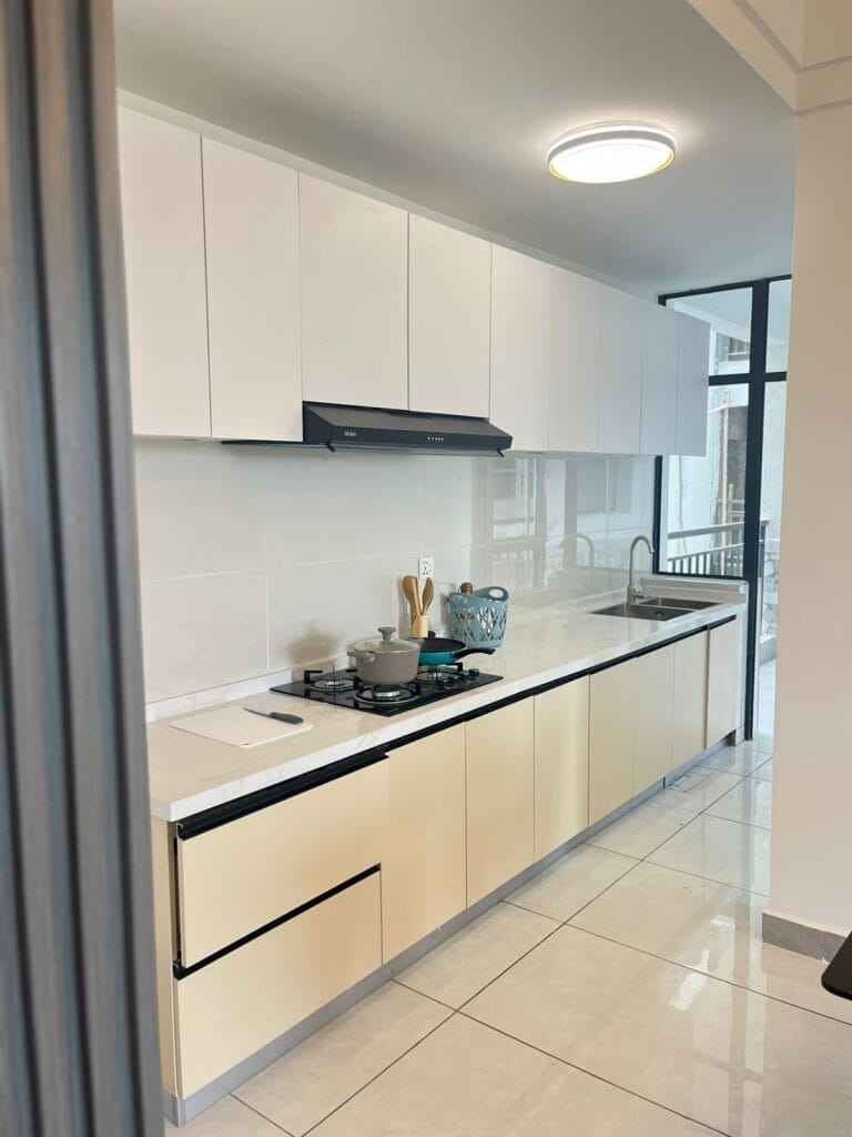 Modern fitted kitchen with sleek upper cabinetry, integrated gas stovetop, extractor hood, and quartz countertops at New Rise Gardens in Syokimau, Nairobi.