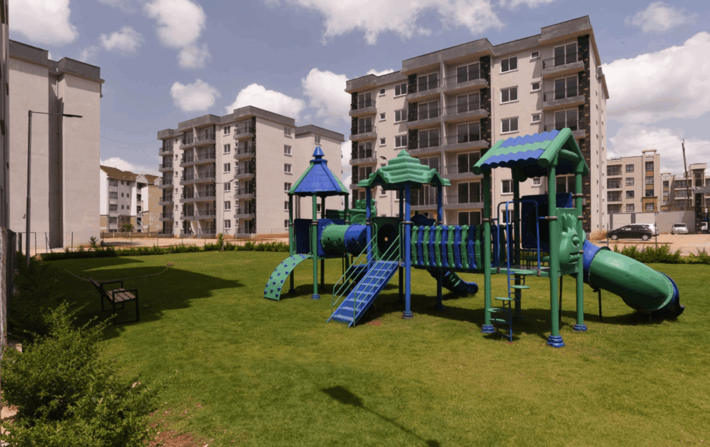 Dedicated children's play park and green lawns set against modern multi-story residential blocks at Sunpark Residences in Syokimau, Nairobi.