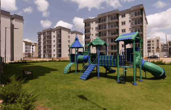 Dedicated children's play park and green lawns set against modern multi-story residential blocks at Sunpark Residences in Syokimau, Nairobi.