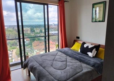 Bedroom interior with sliding balcony door overlooking Lavington skyline at Urban Oasis Lavington