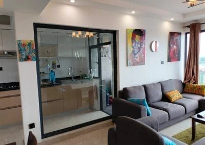 Open-plan living space facing a modern kitchen with glass partition at Urban Oasis Lavington